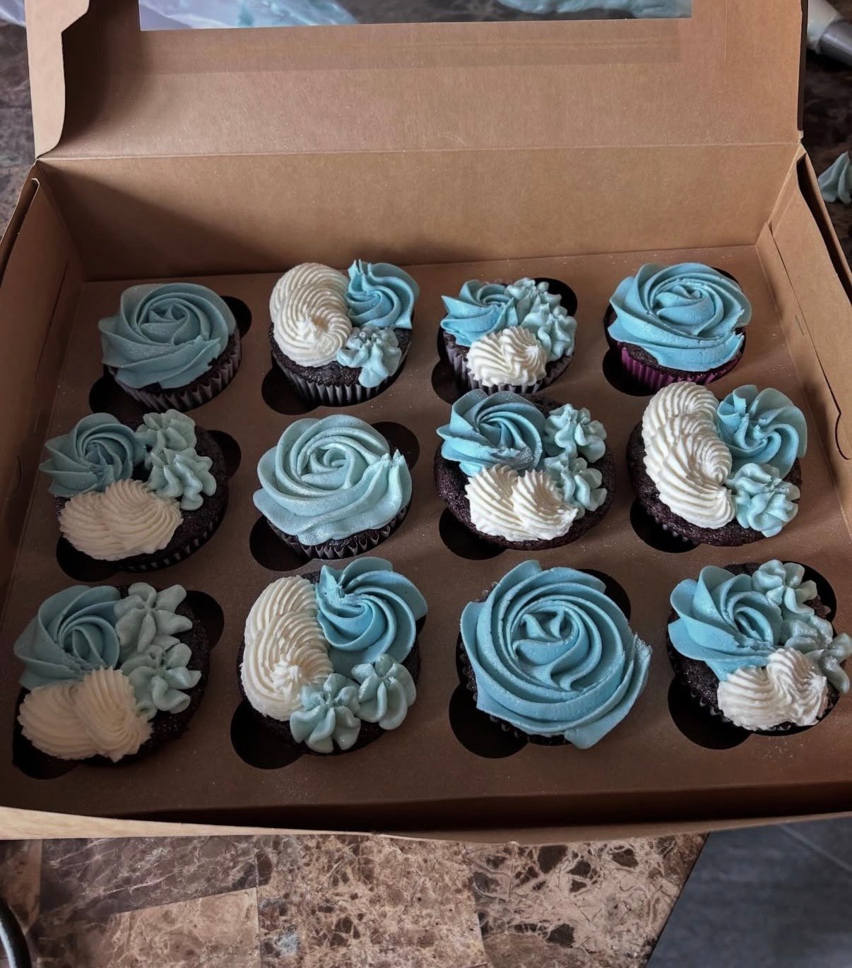 Box of blue and white frosted cupcakes